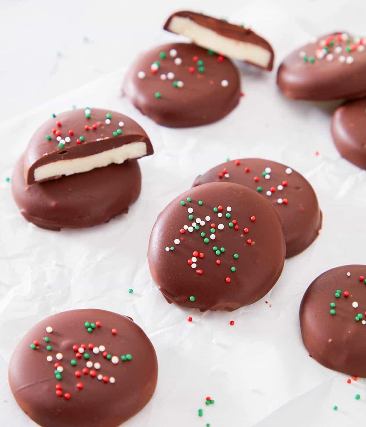 Several pieces of peppermint pies on a white surface with red, white and green sprinkles on top.  Some pieces are cut in half.