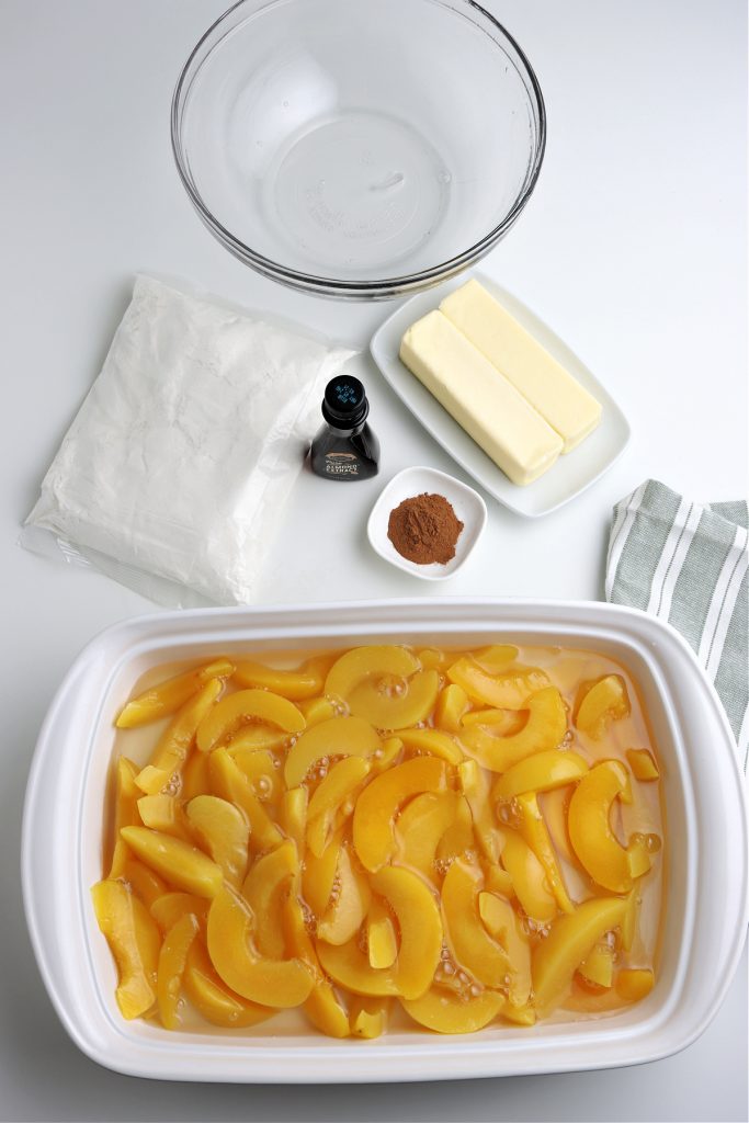 Step one for Dump Cake is peaches in a white baking dish