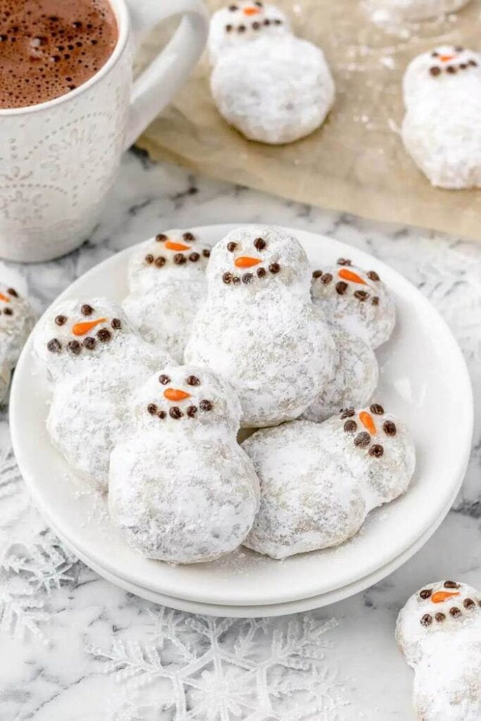 powdered sugar covered cookies decorated to look like snowmen