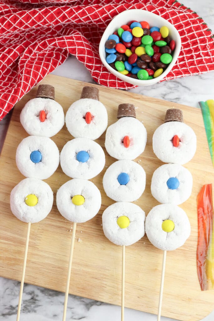 assembling donut snowman treats on sticks