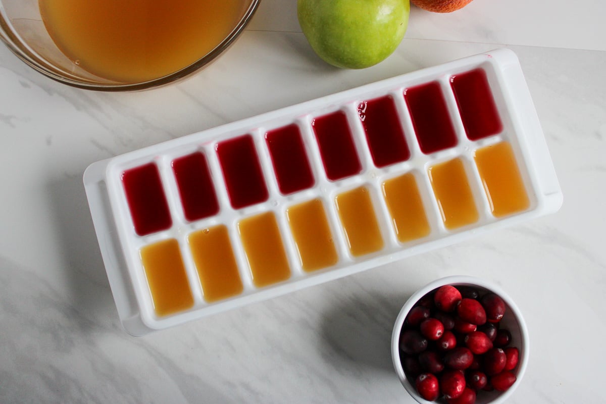 Ice cube tray filled with cranberry juice and apple cider.