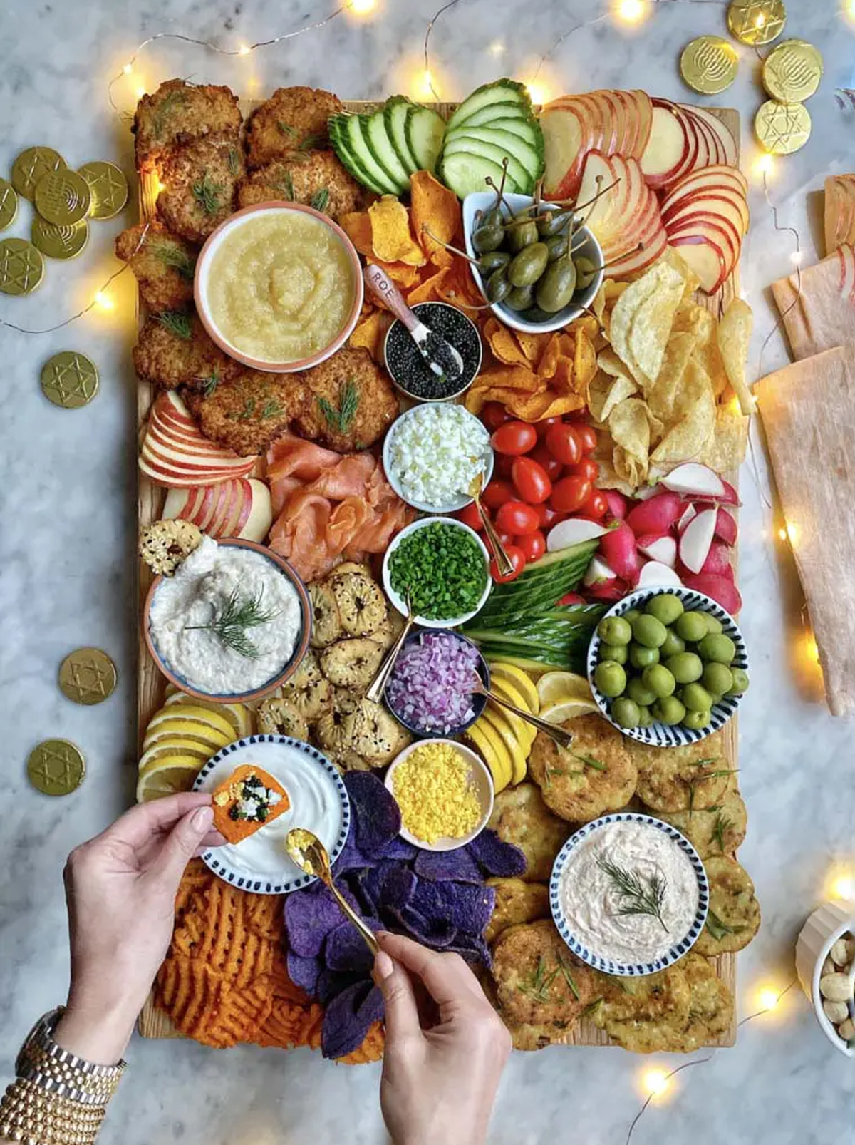 veggies, charcuterie meet, sweet potato fries and chips, along with apple slices, latkes, and dips fill ain't too proud to meg's Hanukkah charcuterie board recipe.