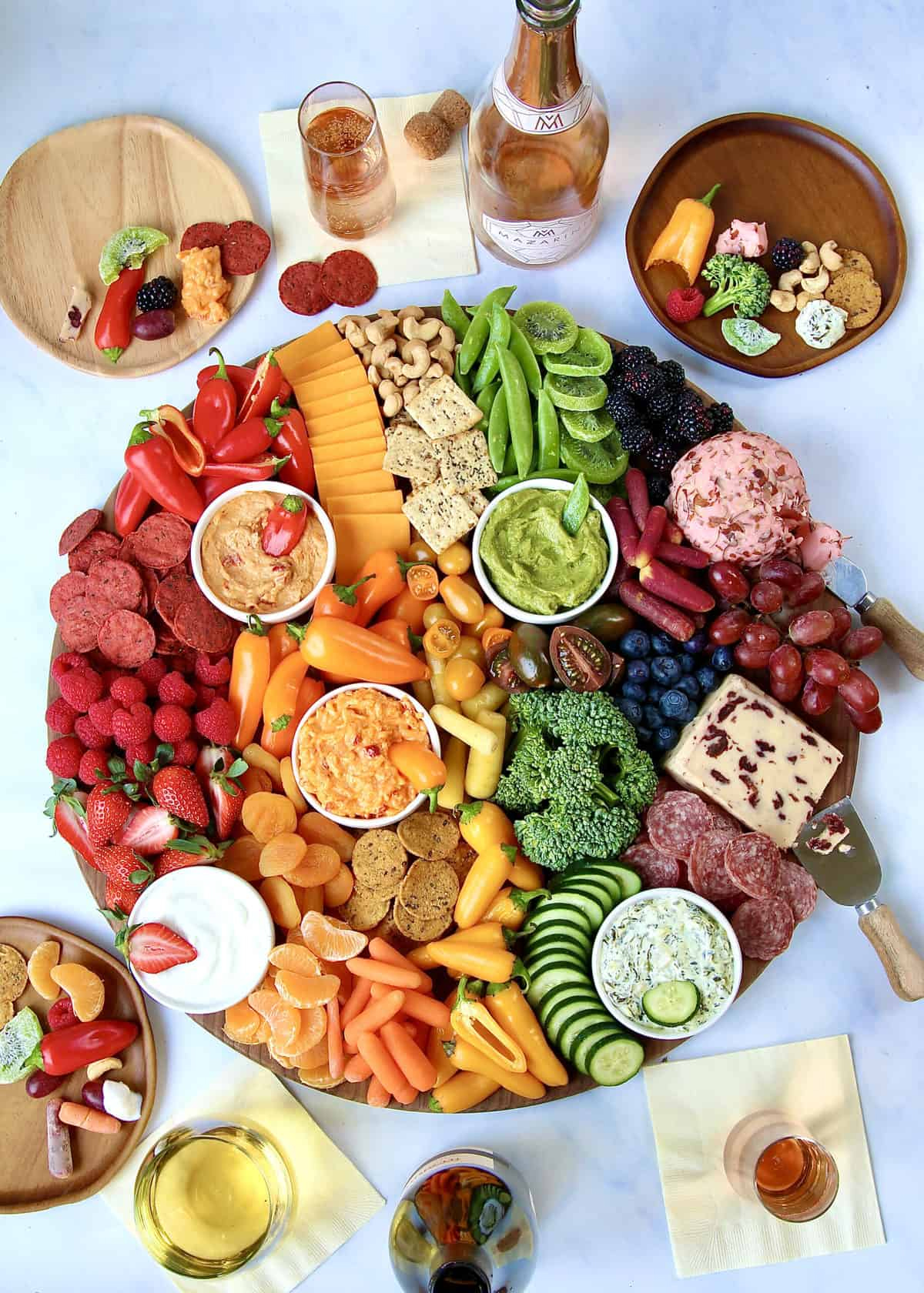 Bakermamas grown up rainbow board with wine, peppers, colorful cheeses, nuts, and more.