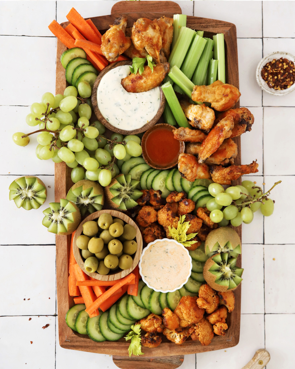 Wings, dips, cucumbers, carrots, celery, and kiwi complete Kayla's Kitch and Fix's Super Bowl snack board.