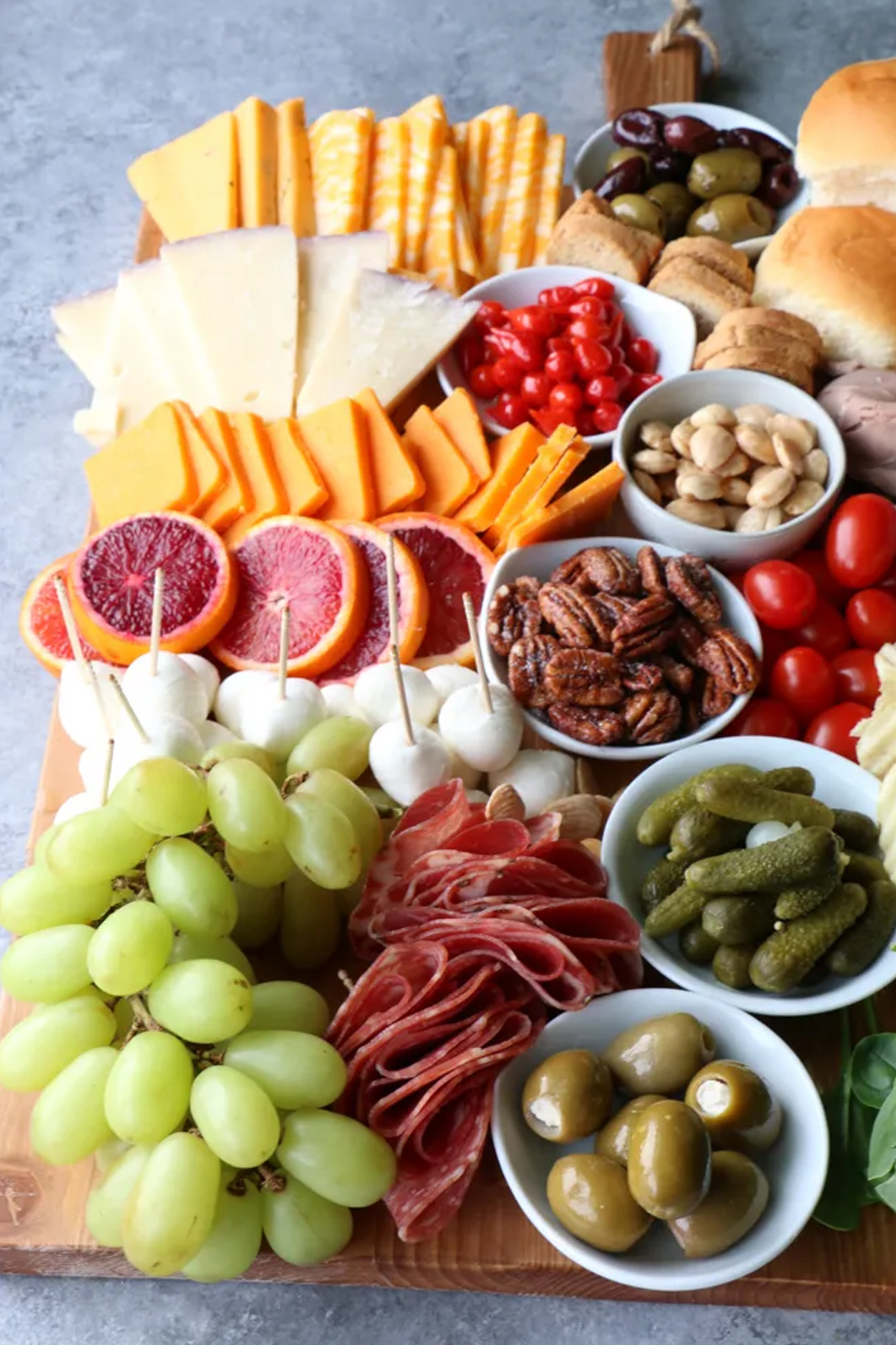 Cheese, meats, olives, buns, nuts, pickles, grapes, and tomatoes fill Hip Foodie Mom's charcuterie board.